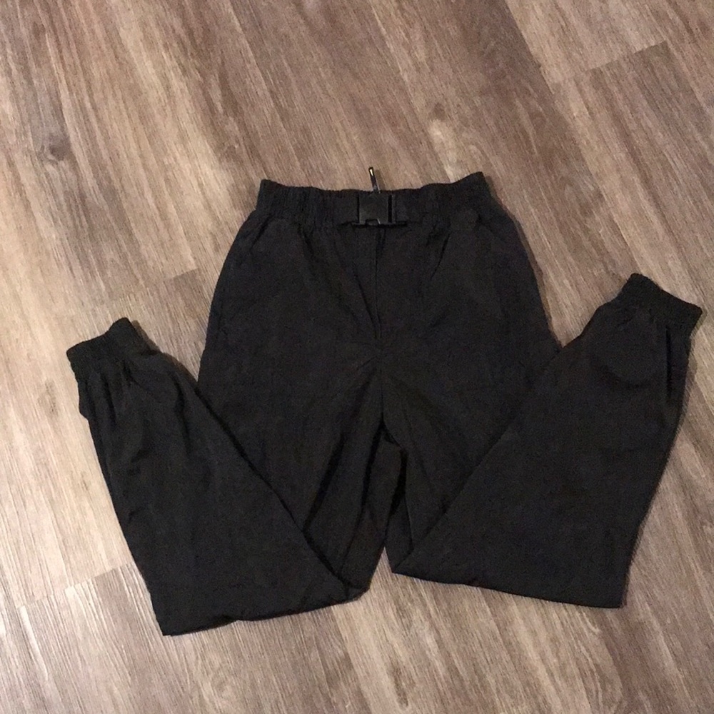 Black small cargo track pants with clip buckle.
